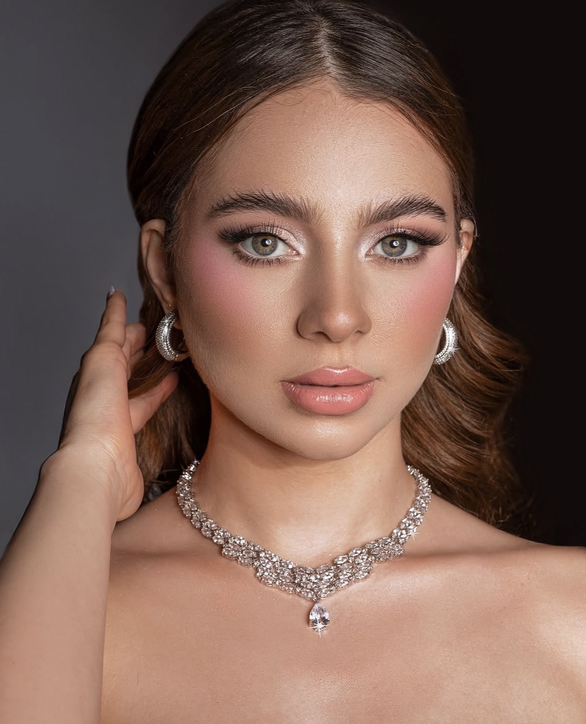 Rose-toned glam makeup, defined lashes and glossy nude lips with a crystal necklace.