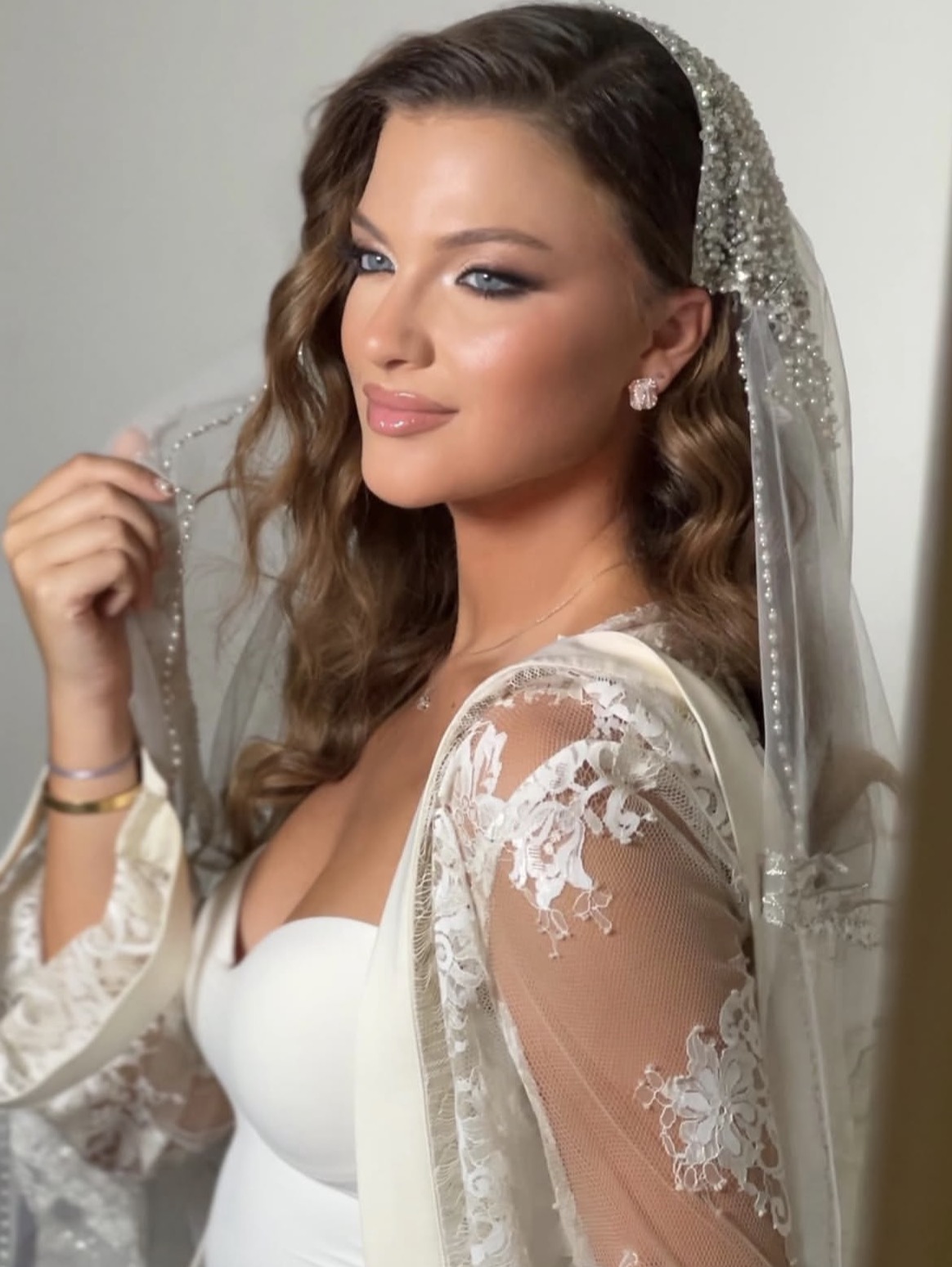 A bridal portrait with softly smoky eyes, pink lips and a pearl-trimmed veil.