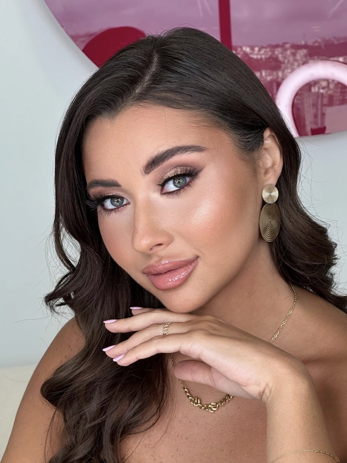 A soft rose smoky eye, defined lashes and glossy pink lips with gold statement earrings.